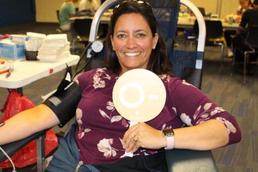 Smiling blood donor in donation chair holding up sign with her blood type. 