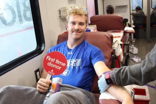 Blood donor in donation chair with First Time Donor sign at Goldey-Beacom College Blood Drive .