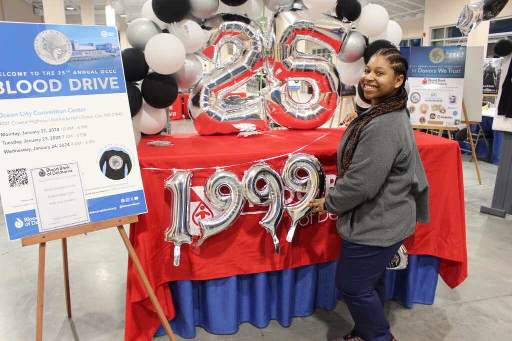 A smiling BBD staff member in front of a table with the number 25 on it.