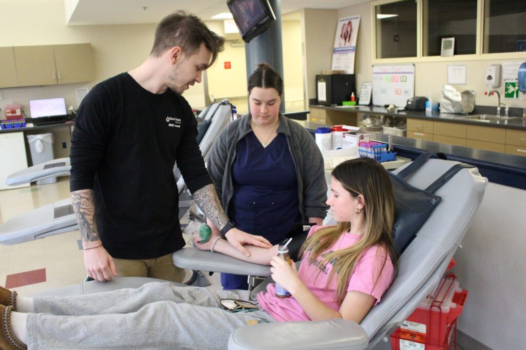 Mackenzie Fanning with BBD staff in a blood donation chair.